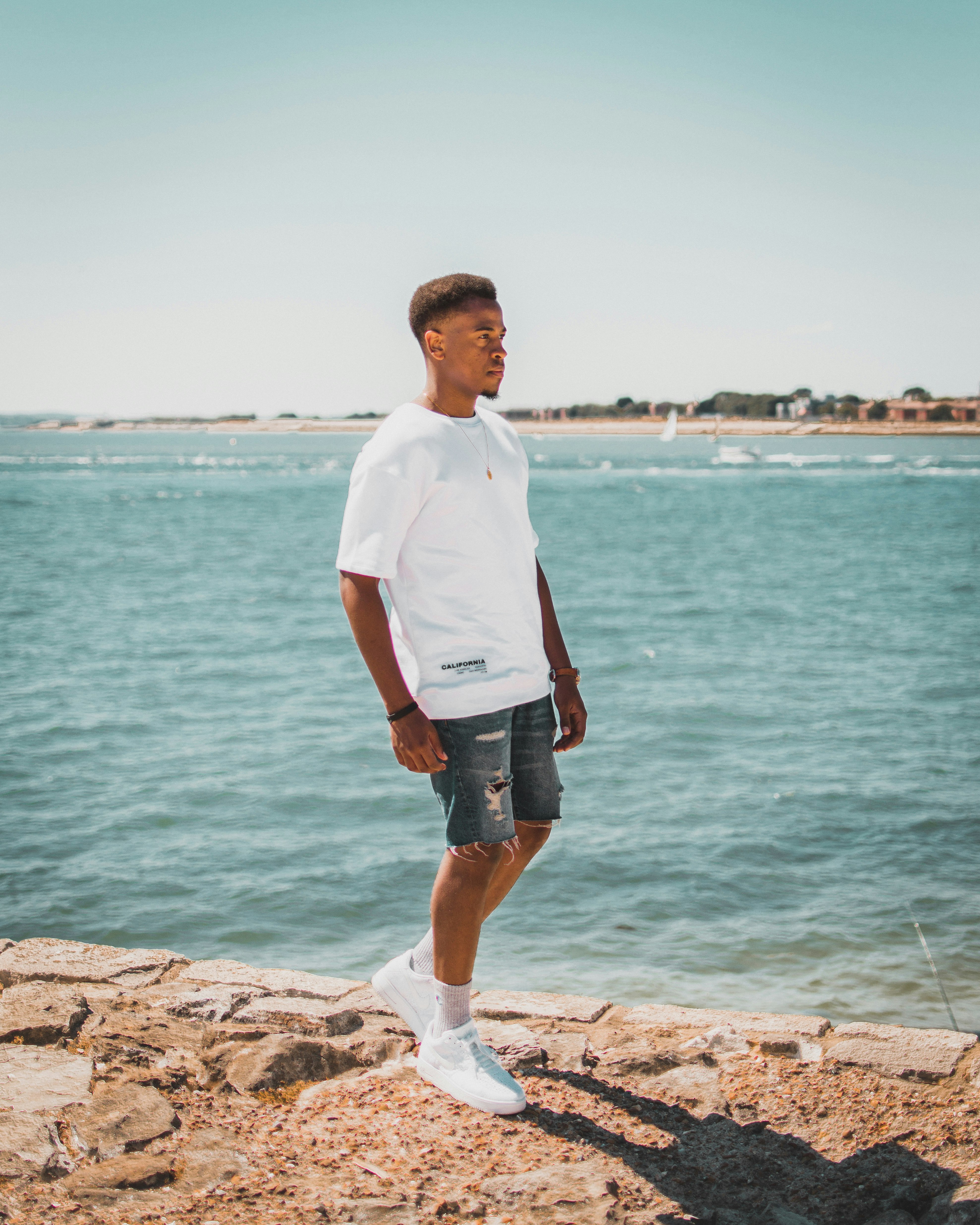 man wearing whiter t-shirt standing near ocean